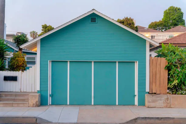 Aqua blue detached garage exterior at Oceanside, California. Garage exterior with bi-fold doors against the houses at thee background.