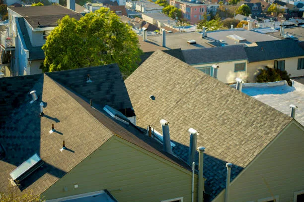 Double gable style rooftops on house seen from a suburban park above the neighborhoods with sprawling city and streets in downtown city. In late evening sunset lighting with visible trees and homes.