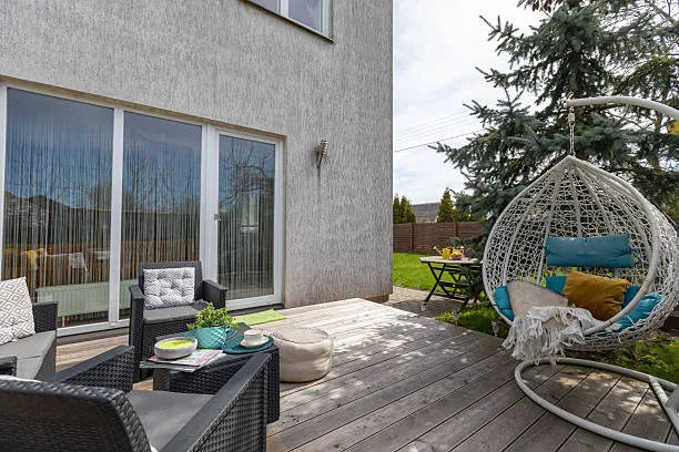 A well-designed garden patio featuring cozy furniture, a wooden deck, greenery, and relaxation accents, creating a warm and inviting outdoor living space perfect for leisure or gatherings