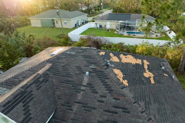 Damaged house roof with missing shingles after hurricane Ian in Florida. Consequences of natural disaster.