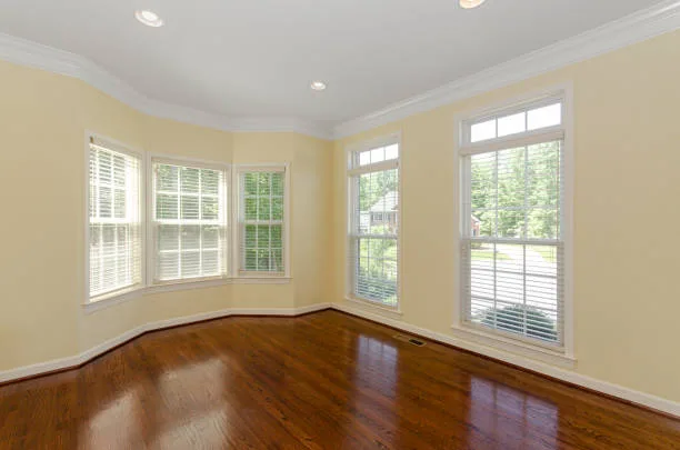 A large, bright room featuring beautiful hardwood floors and numerous windows that allow natural sunlight to gracefully fill the space for a warm atmosphere.