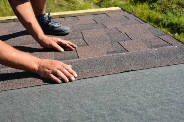 Roofing contractor lay asphalt shingles tiles on house rooftop. Asphalt shingles roofing construction, repair, installation, replace, renovation.