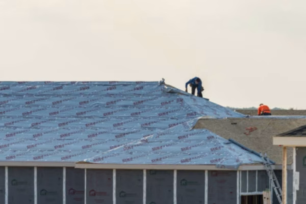 Georgetown, TX - September 17, 2024: Single family home with dimensional lumber frames being covered with CoverPro synthetic roofing underlayment