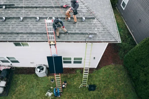 A high angle drone point of view of workers installing solar panel array on the roof of a home in Washington state, USA.  Clean, green, environmentally friendly energy.
