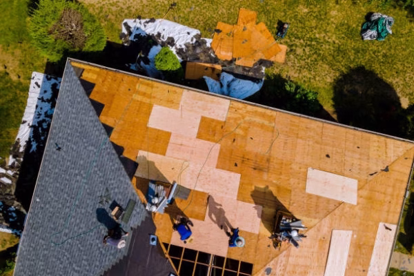 Aerial view of roof construction repairman on a residential apartment with new roof shingle being applied