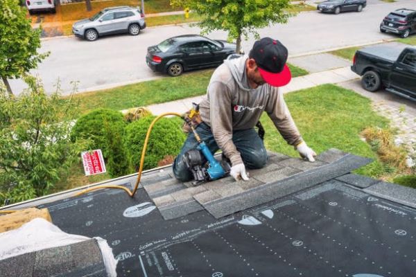 Roofer lays new roof on a house in Brantford, Ontario, Canada on a cloudy day.
