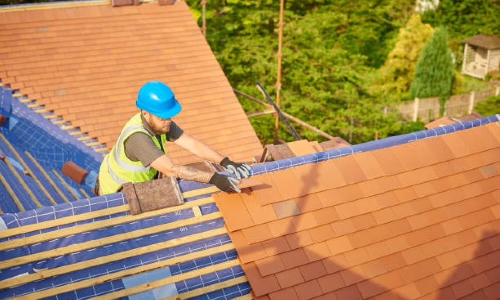 a roofer nails on the roof tiles