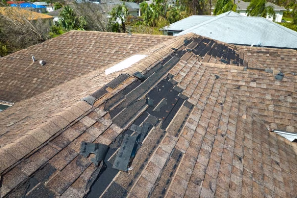 Damaged house roof with missing shingles after hurricane Ian in Florida. Consequences of natural disaster.